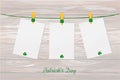 Three blank paper with green clovers hanging on a rope on a wood Royalty Free Stock Photo