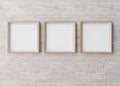 Three blank square picture frames hanging on white brick wall. Template, mock up for your picture or poster. Copy space Royalty Free Stock Photo