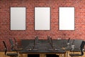 Three blank vertical posters mock up on the red brick wall in office interior.