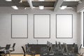 Three blank vertical posters mock up on the white brick wall in office interior.