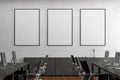 Three blank vertical posters mock up on the white brick wall in office interior. Royalty Free Stock Photo