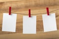 Three blank white note cards hanging with clothespins. Wooden background. Copy space