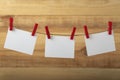 Three blank white paper cards hanging with clothespins on rope string peg on wooden background. Copy space Royalty Free Stock Photo