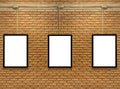 Three blank white poster mock up space frame on brick wall background. Royalty Free Stock Photo