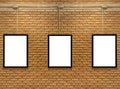 Three blank white poster mock up space frame on brick wall background. Royalty Free Stock Photo