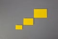 three (3) blank yellow papers of different sizes from smallest to largest arranged diagonally on a gray background Royalty Free Stock Photo