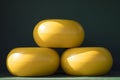 Three blocks of Dutch cheese on green shelf, dark background Royalty Free Stock Photo