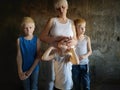 Three blonde brothers pose in Studio next to their mother. Boys and a woman with white bleached hair. family is happy together