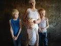 Three blonde brothers pose in Studio next to their mother. Boys and a woman with white bleached hair. family is happy together