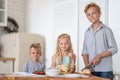 Three blonde kids twoboys and girl on kitchen at home. Family eating healthy food , green salad on plates. Looking at Royalty Free Stock Photo