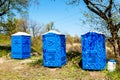 Three Blue Cabines Of Chemical Toilets In Park at sunny Summer Day