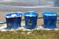 Three blue soapy water buckets in row on sidewalk