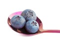 Three blueberries in purple metal spoon.