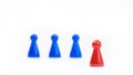 Three blurred blue game pieces as a team and one red sharpened figure as a leader in the foreground. Closeup photo with selective