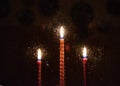 Three blurred red candles burning in the darkness outside the window