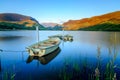 Three boats docked on a lake in Snowdonia National Park before tree slopes under the blue sky Royalty Free Stock Photo