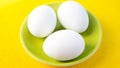 Three boiled eggs on green plate