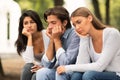 Three Bored Friends Sitting On Bench In Park Outdoors