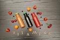 Three bottles with juice, fruit and inscription vitamins on a black wooden background, food concept Royalty Free Stock Photo