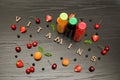 Three bottles with juice, fruits and inscription vitamins on a black wooden background, food concept Royalty Free Stock Photo