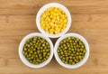 Three bowl with green peas and sweet corn on table