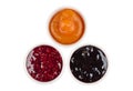 Three bowls with raspberry, peach, blueberry jam isolated on white Royalty Free Stock Photo