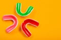 Three boxing mouth guards, red, pink and green, lie on a yellow background, concept, top view Royalty Free Stock Photo