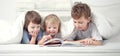 Three boy read book indoors on bed Royalty Free Stock Photo