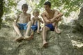Three boys friends talking to each other sitting relaxed on a rock in summer, friendship trust belonging together
