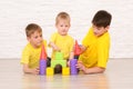 Three boys playing on the floor against a white brick wall Royalty Free Stock Photo