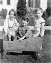 Three boys sitting in a push cart and smiling