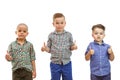 Three boys are standing together on the white background and hold their thumbs up