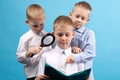 Three boys of 7-9 years old are reading a book. Portrait of Three Boys on a Blue Background Royalty Free Stock Photo