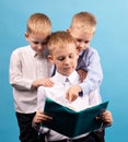 Three boys of 7-9 years old are reading a book. Portrait of Three Boys on a Blue Background Royalty Free Stock Photo