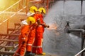 Three brave firefighters using extinguisher and water from hose for fire fighting, Firefighter spraying high pressure water to