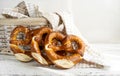 Three brezels or pretzels placed near bread basket with napkin on white wooden background