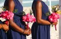 Three bridesmaids in dark blue dress holding pink bouquets at wedding on the beach Royalty Free Stock Photo