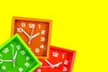 Three bright alarm clocks on a yellow background. Clock table green and orange and red.