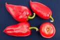 Three bright big red bell peppers and one red tomatoe on blue background top view closeup Royalty Free Stock Photo