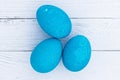 Three bright blue eggs against a background of white wooden planks. Painted colored Easter eggs top view. Set of homemade eggs for Royalty Free Stock Photo