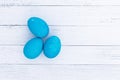 Three bright blue eggs against a background of white wooden planks. Painted colored Easter eggs top view. Set of homemade eggs for Royalty Free Stock Photo