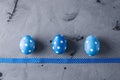 Three bright blue polka dot eggs with a ribbon on a gray background. Festive Easter card Royalty Free Stock Photo