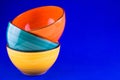 Three bright ceramic bowls in a stack isolated on a blue background.Copy space. Royalty Free Stock Photo