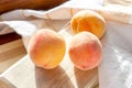 Three bright fresh juicy red and orange peaches on the wooden board in the sunny kitchen in summer. Royalty Free Stock Photo