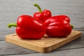 Three bright red bell peppers on old wooden cutting board. Royalty Free Stock Photo