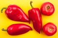 Three bright red peppers and two red tomatoes on yellow background top view close up Royalty Free Stock Photo