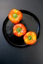 Three red photographed from top peppers in a round black dish