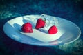 Three bright ripe juicy red strawberries are on a white plate Royalty Free Stock Photo