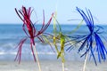 Three bright shiny colored cocktail decorations on stick stand in sand near sea Royalty Free Stock Photo