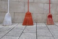 Three brooms of different colors against a wall Royalty Free Stock Photo